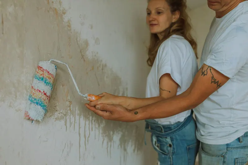 Junge Auszubildende streicht eine Wand mit der Rolle
