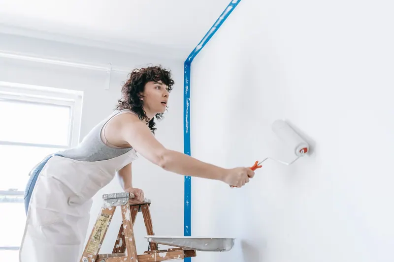 Maler trägt mit der Farbrolle Farbe auf eine Wand auf